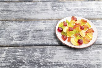 Various fruit jelly candies on plate on gray wooden background. side view, copy space