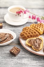 Homemade waffle with chocolate butter and cup of coffee on a gray wooden background. side view,