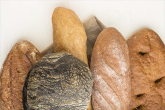 Different kinds of fresh baked bread on a white wooden background. top view, flat lay, close up