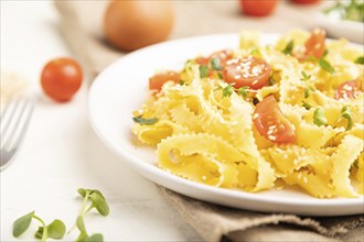 Reginelle semolina pasta with tomato, eggs, sesame and microgreen sprouts on a white wooden