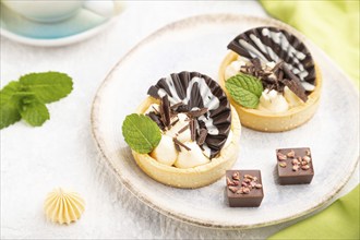 Sweet tartlets with chocolate and cheese cream with cup of coffee on a gray concrete background and