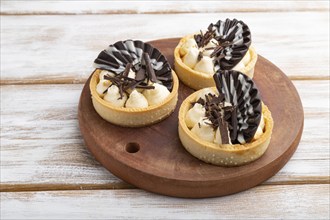 Sweet tartlets with chocolate and cheese cream on a white wooden background. side view, close up