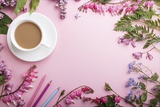 Purple lilac and bleeding heart flowers and a cup of coffee on pastel pink background. Morninig,