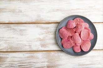 Red potato chips with herbs and tomatoes on white wooden background. Top view, flat lay, copy space