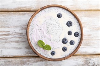 Yogurt with blueberry in wooden bowl on white wooden background. top view, flat lay, close up