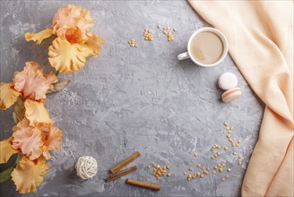 Orange iris flowers and a cup of coffee on a gray concrete background. Morninig, spring, fashion