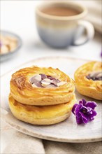 Small cheesecakes with jam and almonds with cup of coffee on a white concrete background and linen