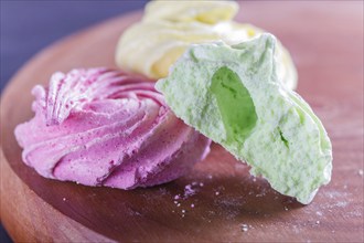 Colored meringues on wooden board, selective focus, close up