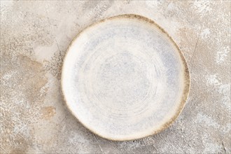 Empty blue and white ceramic plate on brown concrete background. Top view, copy space, flat lay