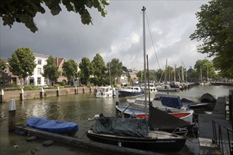 Sailing boats in Maartensgat harbour with dramatic lighting after recent rain storm, Dordrecht,