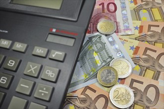 Euro banknotes and coins and pocket calculator