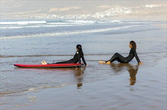 Surfers sitting on beach Atlantic Ocea, Taghazout, Morocco, North Africa, Africa