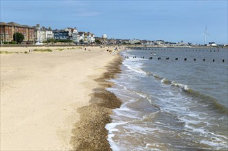 People enjoying sunny weather on sandy South Beach, Lowestoft, Suffolk, England, UK view to town