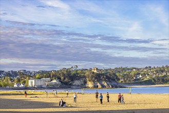 People playing beachvolleyboll on the sand beach by the sea in Morgat village in the evening light,