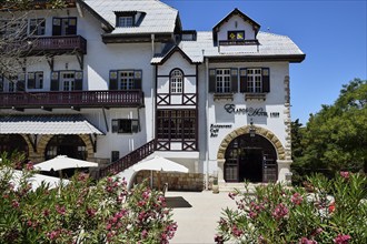 Historic white hotel with half-timbered houses, parasols and plants on a sunny day, Elafos Hotel,