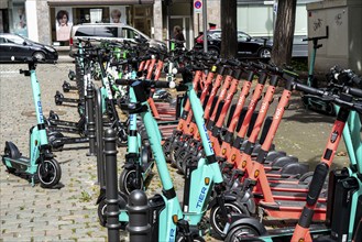 Electric scooters, e-scooters are parked in large numbers on the Burgmauer road, in front of