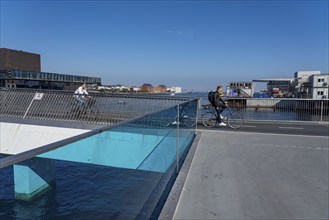 Cyclists on the Inderhavnsbroen cycle and footpath bridge, over the harbour, at Nyhavn, Copenhagen