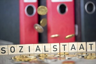 Wooden letters show the word SOCIAL STATE, falling coins knock over the letters (symbolic image)