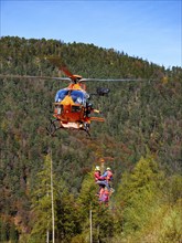 2 mountain rescuers of the Bavarian Mountain Rescue Service are winched by the on-board mechanic of