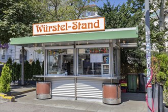 Sausage stand with striking awning in an urban setting and surrounded by greenery, Vienna