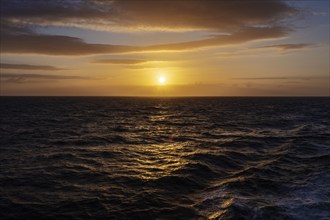 Sunset over a calm sea with clouds and a shimmering orange sky, Celtic Sea