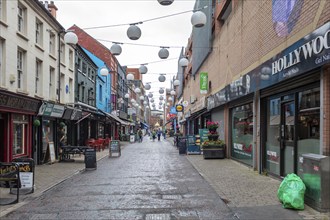 Busy shopping street with shops and colourful signs on a rainy day, Belfast