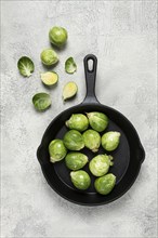 Fresh Brussels sprouts, raw, in a cast-iron pan, top view, on a gray table, no people