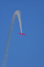 Red stunt aerobatic plane inverted flying loop performing stunts in blue sky. Concept of speed,