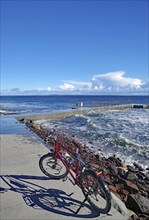 Sun shining on a bicycle on a coastal promenade with a view of the sea and waves, Tönsberg,