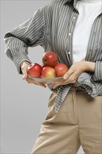 Cropped image of unrecognizable woman holding plate with apples in her hans