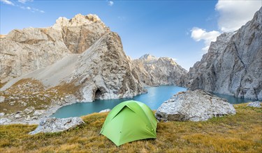 Green tent at the turquoise mountain lake Kol Suu with rocky steep mountains, Kol Suu Lake, Sary