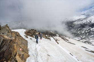 Mountaineer on a rocky ridge with snow, descent from the summit of Schönbichler Horn, view of