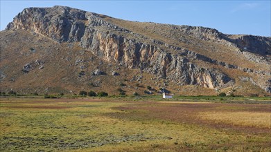 A small white chapel at the foot of a mountain surrounded by meadows, Strofilia biotope, wetlands,