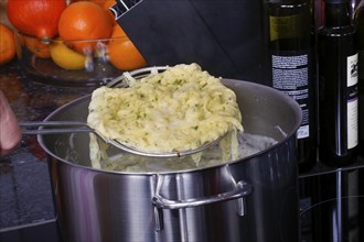 Swabian cuisine, preparation of herb spaetzle for roast beef, scooping spaetzle from boiling water,