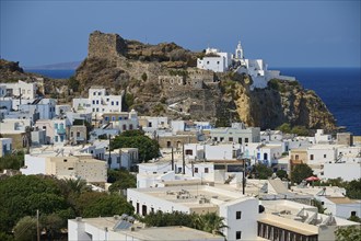 Whitewashed buildings and a historic castle stretch across a rocky hill overlooking the deep blue