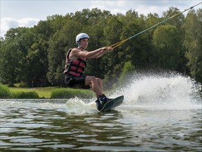 Young man on wakeboard in splashing water, water skiing and wakepark, water sports, Stráž pod