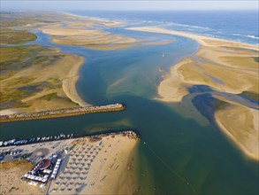 Wide estuary merging into the sea with beaches and boats along the coast, aerial view, Fuseta,