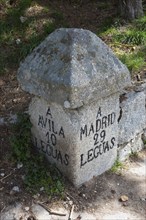 An old stone milestone with inscriptions shows the distance to Avila and Madrid, old stone signal,