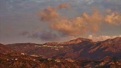 Mountain landscape at sunrise with dramatic clouds and a warm, atmospheric ambience, Pigadia, town