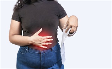 Woman with stomach problems holding roll of paper. Person with stomach pain holding paper roll