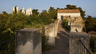 View through old walls to a church surrounded by trees in the soft evening light, Koroni, Byzantine