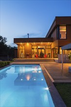 Rear of modern cube style home with stained horizontal wood cladding, in-ground swimming pool and