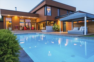 Rear of modern cube style home with stained horizontal wood cladding, in-ground swimming pool and