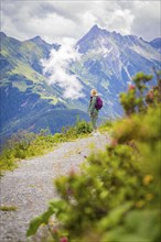 Woman enjoying the view of a picturesque mountain landscape on a hiking trail surrounded by