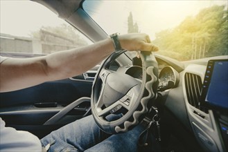 Person hands on the steering wheel driving the car. Close up of hands driving the car