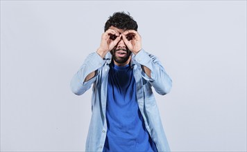 Man making binoculars gesture isolated. Curious man making binoculars gesture isolated