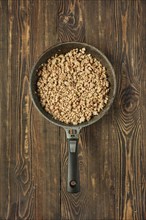 A skillet with browned, cooked ground meat on a rustic wooden table, ready to be incorporated into