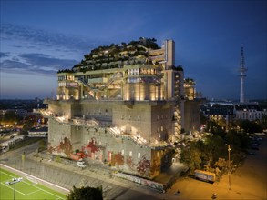 Hamburg bunker with green roof, external stairs and stylish lights in an urban setting at blue hour