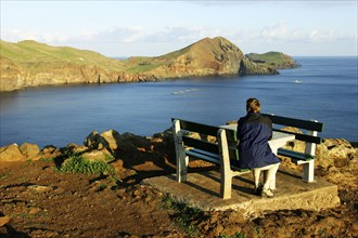 Hiker resting on bench at rocky coast, peninsula Ponta de Sao Lourenco, Madeira, Portugal, Hiker