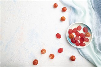 Jelly tomato candies on white concrete background and blue linen textile. copy space, top view,